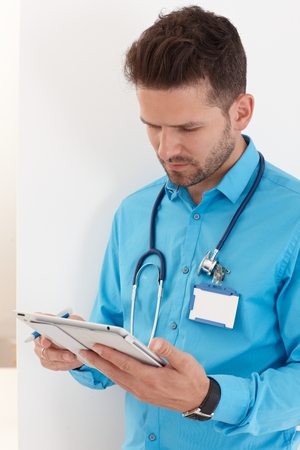 Young male doctor holding tablet computer, working.の写真素材
