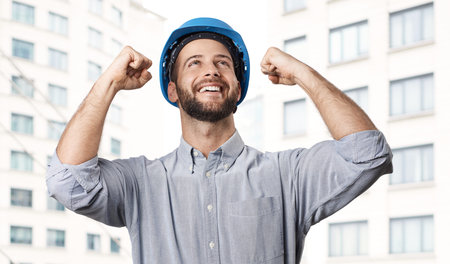 Real estate development - happy excited engineer celebrating success in front of new building.
