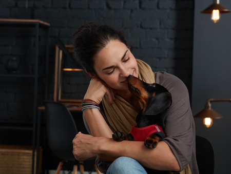 Mature woman with little dog in love at home.の写真素材