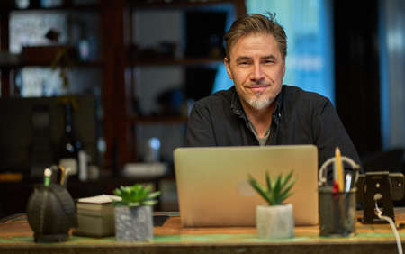 Man working with laptop in home office sitting at deskの写真素材