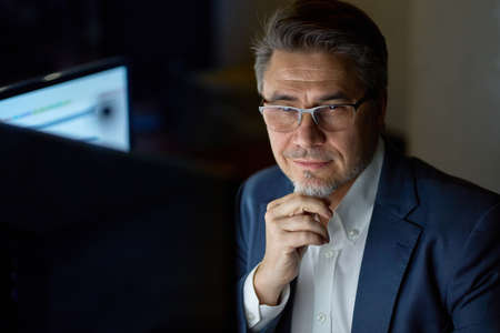 Businessman working with computer at office desk, thinkingの写真素材