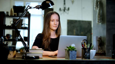 Businesswoman with laptop managing small business in home officeの写真素材