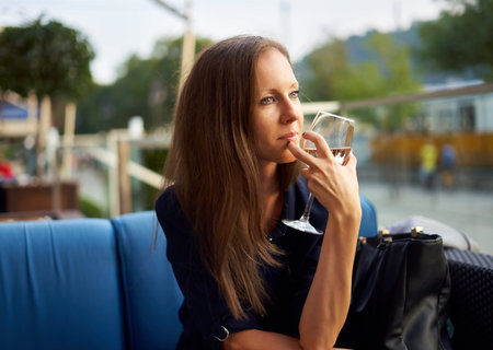 Elegant woman sitting outdoor drinking wine