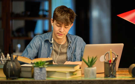 Teenage student learning at home with books and laptop computerの写真素材