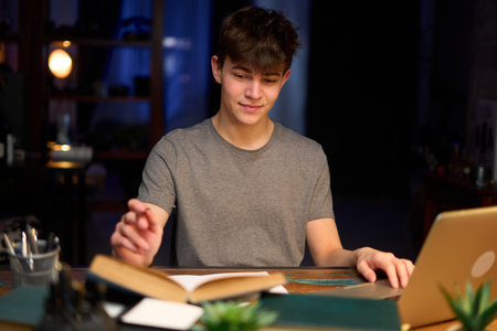 Teenage student learning at home with books and laptop computer