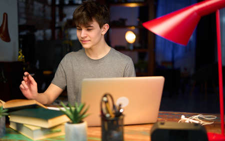 Teenage student learning at home with books and laptop computerの写真素材