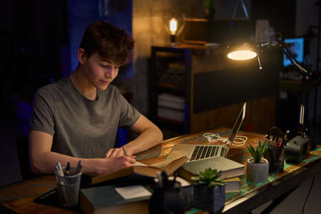 Teenage student learning at home with books and laptop computerの写真素材