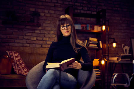 young woman reading a book at homeの写真素材