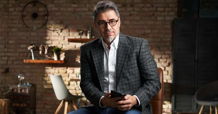 Stay at home - Smart looking older business man in home office using mobile phone for work.の写真素材