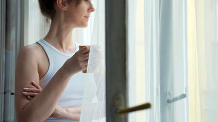 Woman at home drinking morning coffee in windowの写真素材