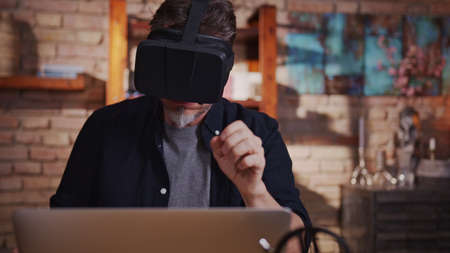 Man working with virtual reality googles at home with laptop computer on deskの写真素材