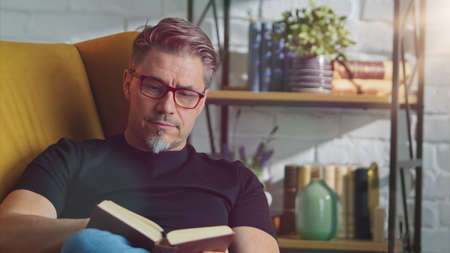 Older white man in glasses reading at homeの写真素材
