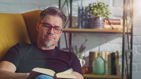 Older white man in glasses reading at homeの写真素材