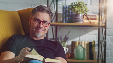 Older white man in glasses reading at homeの写真素材