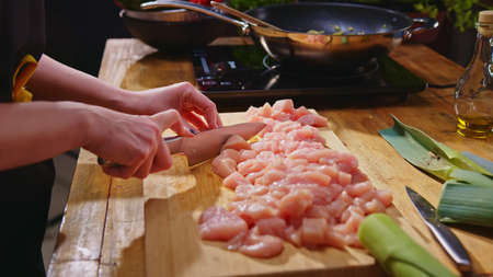 Woman slicing meat for cooking in kitchenの写真素材
