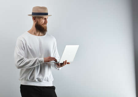 Bearded man with laptop against white wallの写真素材