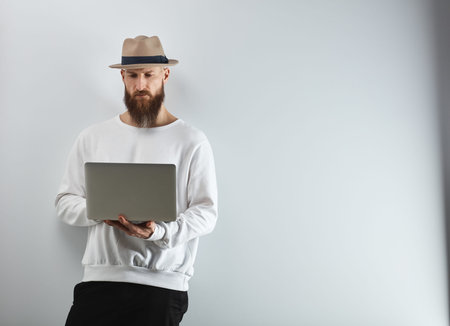 Bearded man with laptop against white wall