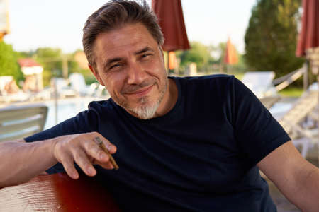 Portrait of mid adult man smoking cigar outdoorの写真素材