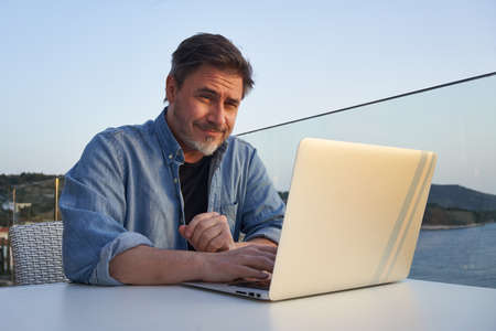 Man working with laptop at home office on terraceの写真素材