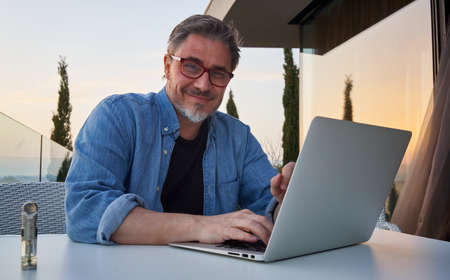 Man working with laptop at home office on balconyの写真素材