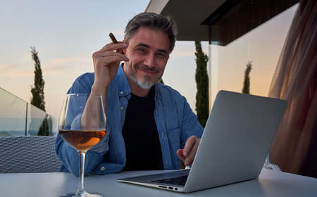 Man relaxing with wine and cigar at homeの写真素材