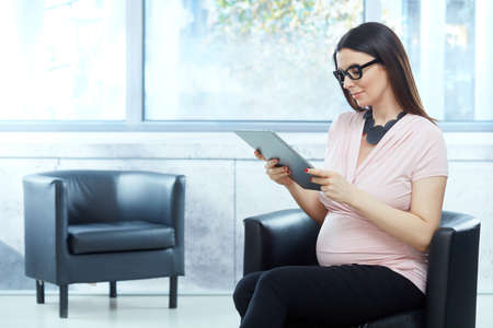 Happy pregnant woman working in modern officeの写真素材