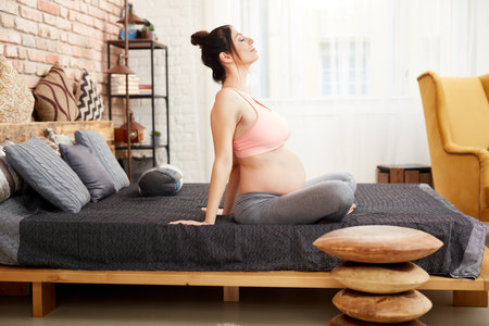 Pregnant woman exercising relaxing at homeの写真素材