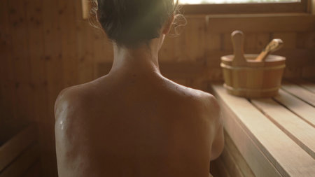 Woman relaxing and sweating in hot sauna. Real, authentic sauna moment.の写真素材