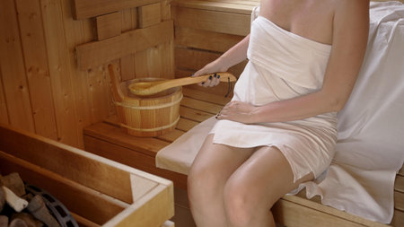 Woman relaxing and sweating in hot sauna. Real, authentic sauna moment. Sauna stove and stone.の写真素材