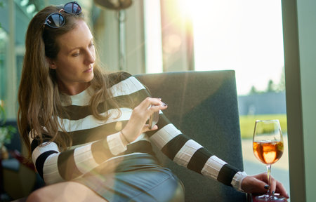 Blogger woman taking photo of a glass of wine or cocktail with phone.の写真素材