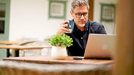 Businessman in home office. Middle aged man working with laptop computer at home outdoor on terrace. Online work, concentration, serious. .の写真素材