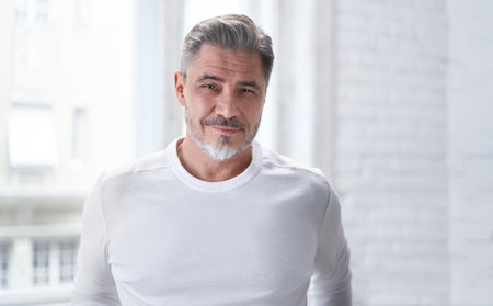 Portrait of mature age, middle age, mid adult casual man at home, happy smiling. Confident smile, gray hair, copy space.の写真素材