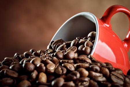 Red ceramic coffee Cup lying in the hot coffee beans.の写真素材