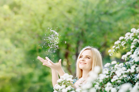 Beautiful young woman standing in a lush white garden.の写真素材