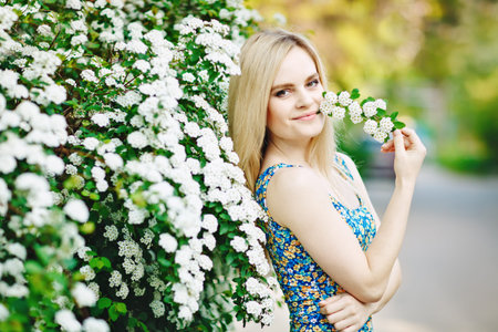 Beautiful young woman standing in a lush white garden.の写真素材
