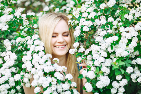 Beautiful young woman standing in a lush white garden.