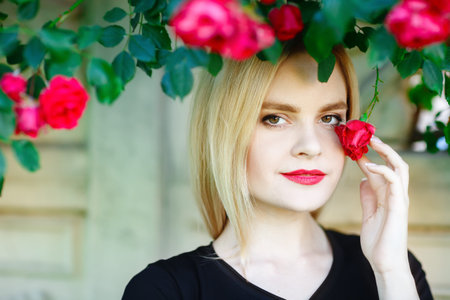 Beautiful young woman in a garden with roses.の写真素材