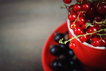 Ripe red and black currants on a wooden table.の写真素材
