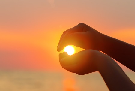 Sunset over the sea. The sun in a childs hand.の写真素材