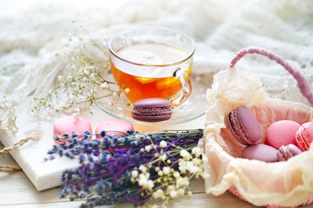 Tea with lemon, wild flowers and macaron on white wooden table.の写真素材