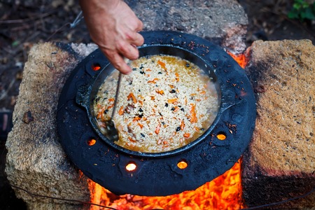 The man cooks national pilaf in a cauldron outdoors.の写真素材