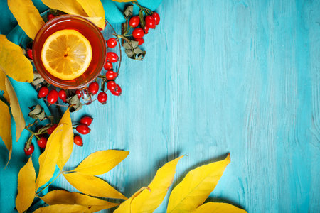The table, decorated with autumn leaves, berries and fresh tea. Autumn. Autumn background.