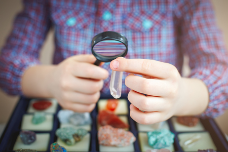 The child looks at his collection of minerals. The little geologistの写真素材