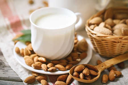 Almond and almond milk on a wooden table in the summer garden. Useful food.の写真素材