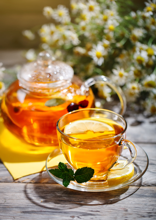 Cup with hot tea with mint and a thyme on a wooden table in a summer garden.の写真素材