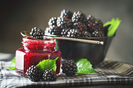 Ripe blackberry and blackberry jam on a wooden table. Dark background.の写真素材