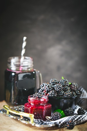 Ripe blackberry, blackberry juice and jam on a wooden table. Dark background.の写真素材