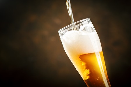 A glass of beer on a dark background.の写真素材