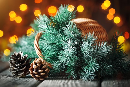 Merry Christmas and happy New year. Basket with branches of the Christmas tree on a wooden table on the background of a garland. Background with copy space. Horizontal.の写真素材