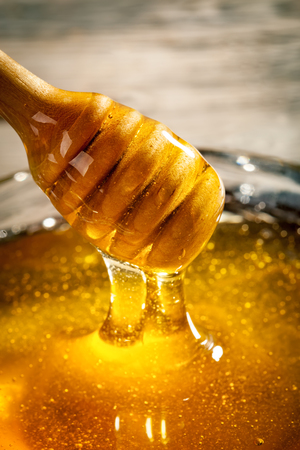 Honey with gold color flows down from a spoon. Healthy food concept. Healthy eating. Diet. Selective focus.の写真素材